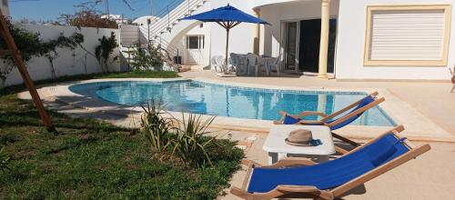 een zwembad met 2 ligstoelen en een parasol bij Chambres d'hôtes Conviviales avec piscine privée Chambre Namasté et Chambre Rose des Sables in Djerba