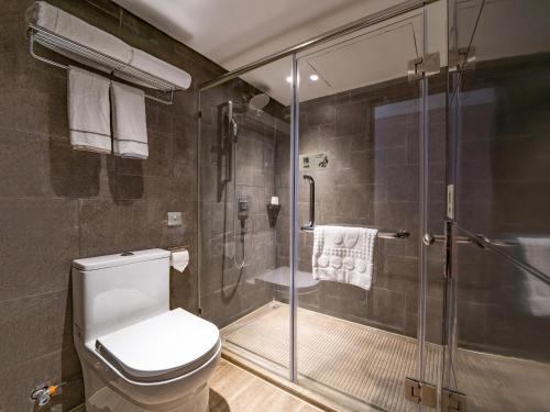 a bathroom with a toilet and a glass shower at Yishang Hotel - Guangzhou Railway Station Yuexiu Park Subway Station in Guangzhou