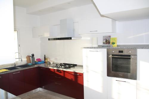 a kitchen with white appliances and red cabinets at Chambres d'hôtes Conviviales avec piscine privée Chambre Blue Lagune & Suite Azur in Djerba