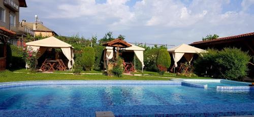 uma grande piscina num quintal com guarda-sóis em Sharkov Family Hotel em Ognyanovo