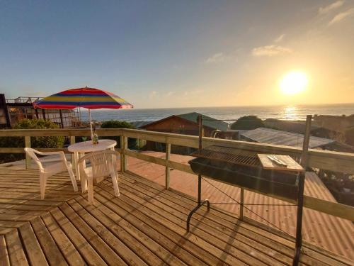 una terraza de madera con mesa y sombrilla en "Suite Dreams" Descanso Cerca del Mar, en El Quisco