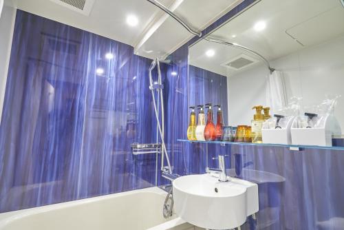 baño con cortina de ducha azul y lavamanos en HOTEL VINE OSAKA KITAHAMA en Osaka