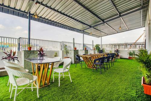 a patio with tables and chairs on the grass at FabHotel W Grand Suites in Hyderabad