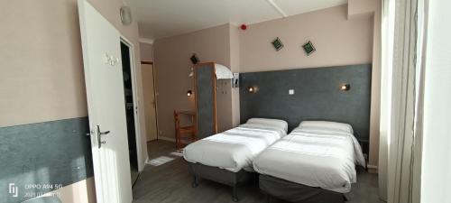 Habitación con 2 camas y puerta a un dormitorio en Hotel du 6 juin, en Sainte-Mère-Église
