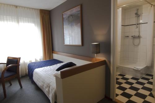 a bedroom with a bed and a bathroom with a shower at Hotel Boer Goossens in Den Dungen