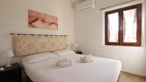 1 cama blanca en un dormitorio blanco con ventana en Welcomely - MareSole La Cinta, en San Teodoro
