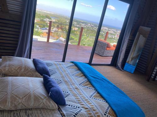 - un lit avec des oreillers bleus devant une fenêtre dans l'établissement Villa Calme et Vue au RDV/Piscine/Plage 10 min, à L'Étang-Salé