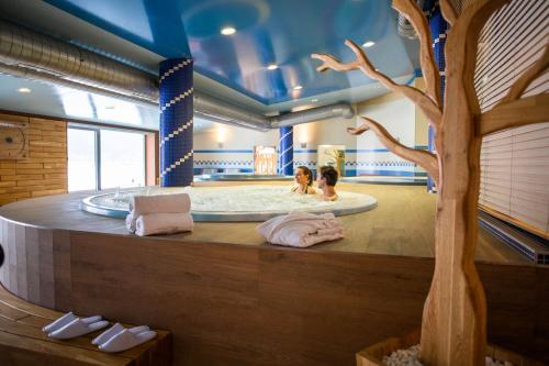 two people in a jacuzzi tub with a tree at Amenity Hotel & Resort Lipno in Lipno nad Vltavou