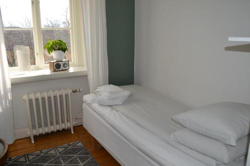 a bedroom with a bed with a radiator and a window at Lilla Hotellet Bed & Breakfast i Alingsås in Alingsås