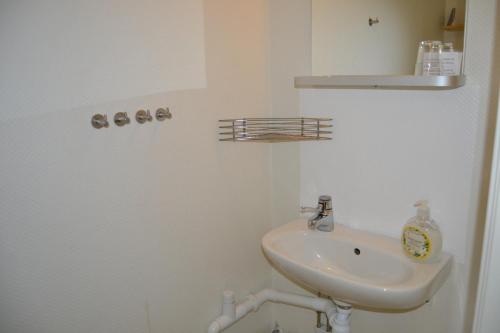a white bathroom with a sink and a shelf at Lilla Hotellet Bed & Breakfast i Alingsås in Alingsås