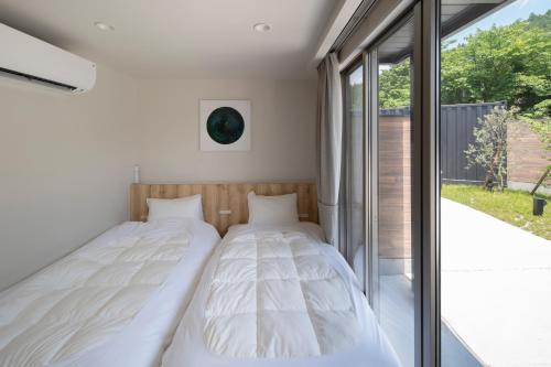 Duas camas num quarto com uma janela em SEN.RETREAT CHIKATSUYU em Tanabe