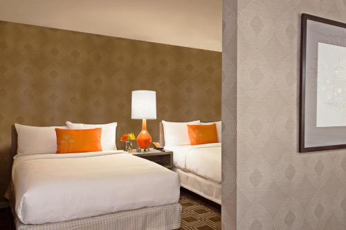 two beds in a hotel room with orange pillows at The Garland in Los Angeles