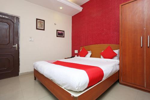 a bedroom with a bed with a red wall at Flagship Hotel Gurukripa in Raipur