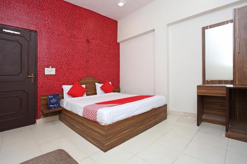 a bedroom with a bed and a red wall at Flagship Hotel Gurukripa in Raipur