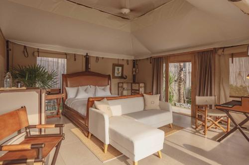 a bedroom with a bed and a couch and a table at Aladdin Luxury Camp Phuket in Phuket
