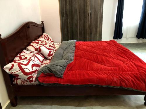 1 cama con manta roja y almohadas en Aberdare Home en Othaya