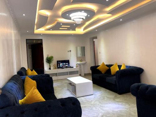 a living room with blue couches and yellow pillows at Aberdare Home in Othaya