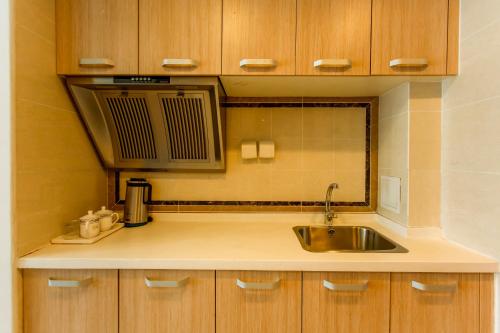 eine Küche mit einer Spüle und einer Mikrowelle in der Unterkunft Dalian Hong Xi Yuan Apartment Wanda Plaza in Dalian