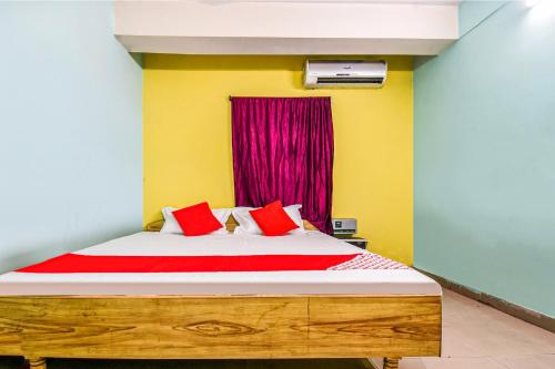 a bedroom with a bed with red pillows and a window at OYO Hotel River View in Patna