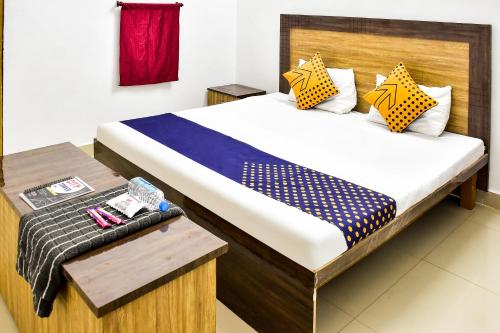 Schlafzimmer mit einem Bett mit einem Kopfteil aus Holz und einem Tisch in der Unterkunft SPOT ON City Tower Inn in Jāmul