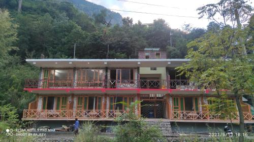 a house with balconies on the side of it at OYO Kamal Guest House Tirthan in Banjār