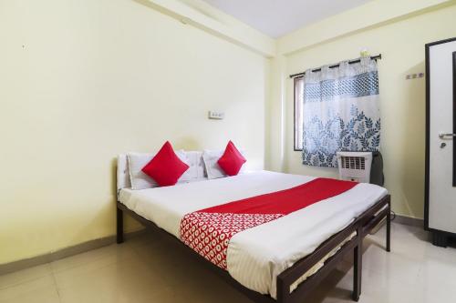 a bedroom with a bed with red and white pillows at OYO Ruby Grand Inn in Kondapur