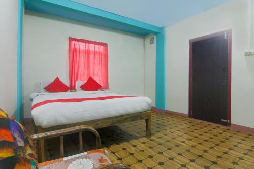 a bedroom with a bed with red pillows and a window at OYO Bell's Bigxa Homestay in Cherrapunji