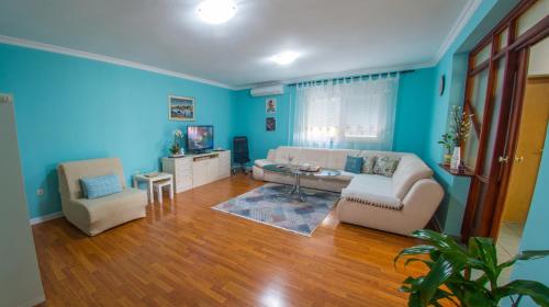 een woonkamer met blauwe muren en een bank en stoelen bij Bega Apartman in Mostar