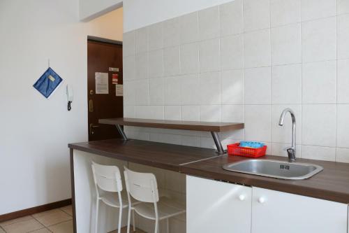 a kitchen with a sink and two white stools at Le Residenze Della Poetessa in Corsico