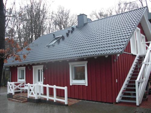 ein rotes Haus mit weißem Geländer und einem weißen Zaun in der Unterkunft Ferienwohnung Studiowohnung, offener Wohn- und Schlafber in Langgöns