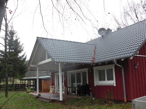 une maison rouge avec un toit en pente dans l'établissement Ferienwohnung Studiowohnung, offener Wohn- und Schlafber, à Langgöns