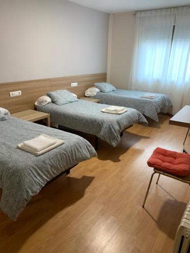 3 camas en una habitación con suelo de madera en Pension Valcarce en Ponferrada