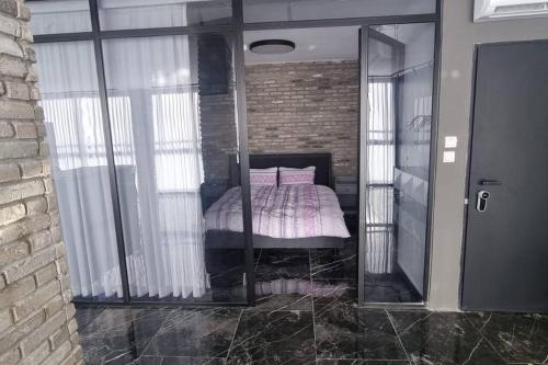 - une chambre avec des portes en verre et un lit avec des oreillers roses dans l'établissement דירה מדהימה עם ג'קוזי, à Qiryat Binyamin