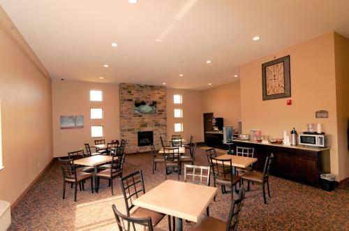 une salle à manger avec des tables, des chaises et une cheminée dans l'établissement Cobblestone Inn & Suites - Denison | Oak Ridge, à Denison