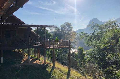 een houten loopbrug naast een huis op een heuvel bij BaanRai KhunYa บ้านไร่คุณย่า in Sai Yok