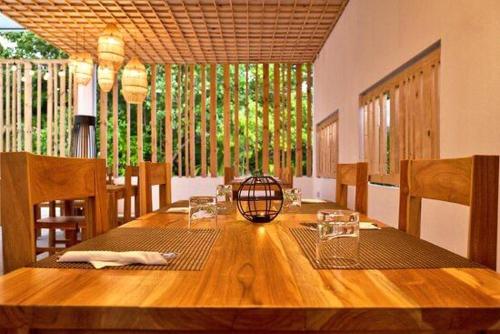 uma sala de jantar com uma mesa de madeira com cadeiras em Trip Villa em Ukulhas