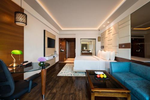 a hotel room with a bed and a blue couch at Radisson Jaipur City Center in Jaipur