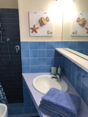 a blue tiled bathroom with a sink and a mirror at TERRATETTO SUNSET in Capoliveri