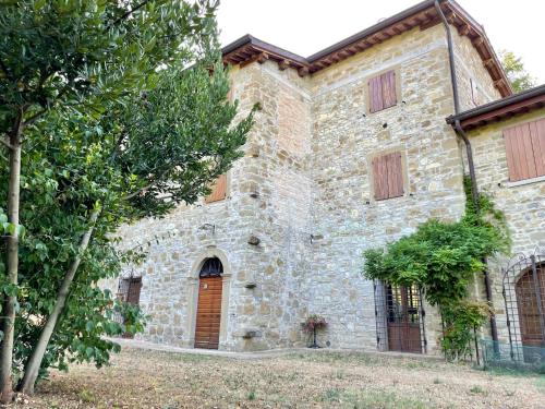 un antiguo edificio de piedra con una puerta marrón y árboles en Sambuco di Sopra en Fratticciola Selvatica