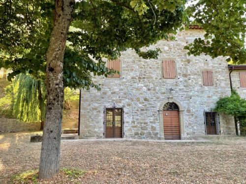 un edificio de piedra con un árbol delante de él en Sambuco di Sopra en Fratticciola Selvatica