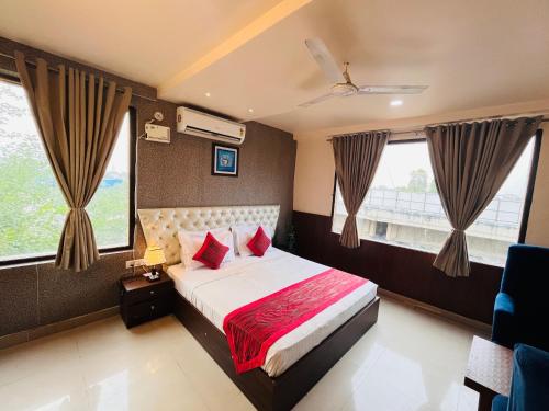 a bedroom with a bed with red pillows and windows at Hotel The Leaf - Gomti Nagar Lucknow in Lucknow