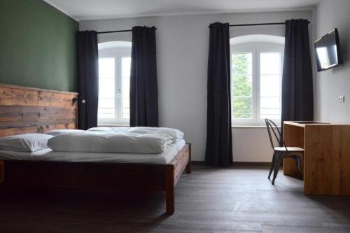 a bedroom with two beds and a desk and two windows at Genusswerk Krug SB Hotel in Bad Endorf