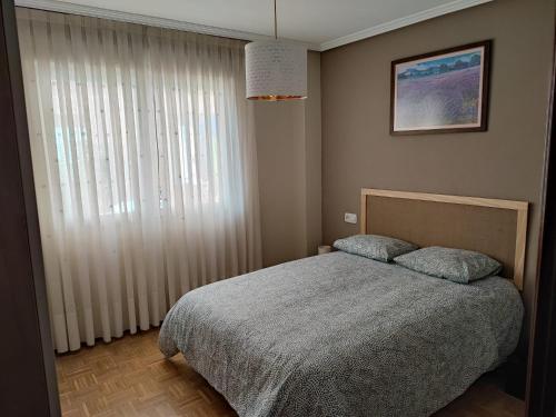 um quarto com uma cama e uma grande janela em Vivienda vacacional cuatrocaminos em Berrón