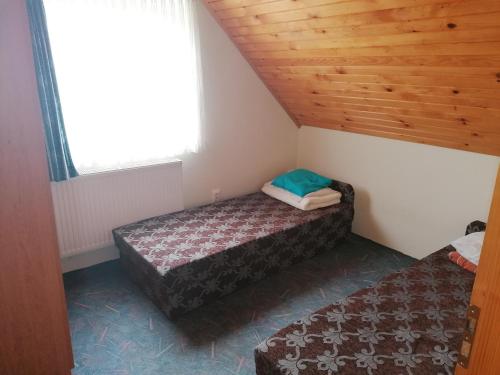 two beds in a small room with a wooden ceiling at Sarkifény Vendégház in Vásárosnamény