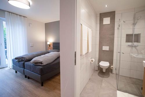a bedroom with a bed and a bathroom with a shower at Boardinghouse Lingen in Lingen
