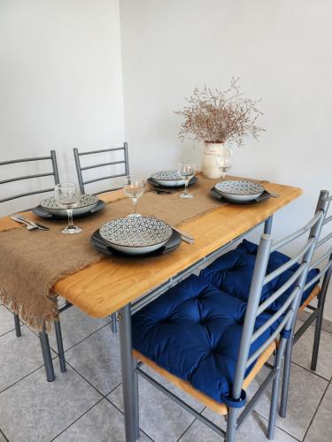 une table en bois avec des assiettes et des verres dans l'établissement Serenita verde Apartment, à Poros