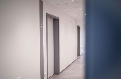 an empty hallway with white walls and a blue door at Boardinghouse Lingen in Lingen