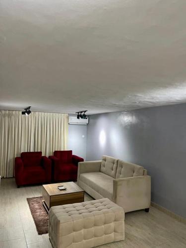 a living room with a couch and red chairs at The GA Apartment in Abeokuta