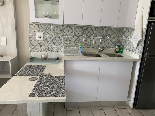 a kitchen with white cabinets and a sink at Uvongo Chalet 11 in Margate