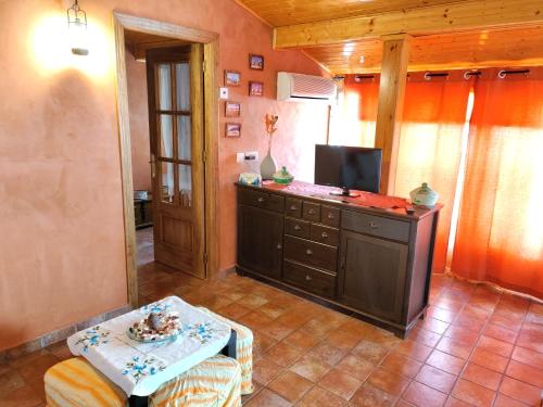 sala de estar con TV y mesa en una habitación en Apartamentos El Mirador en Candeleda